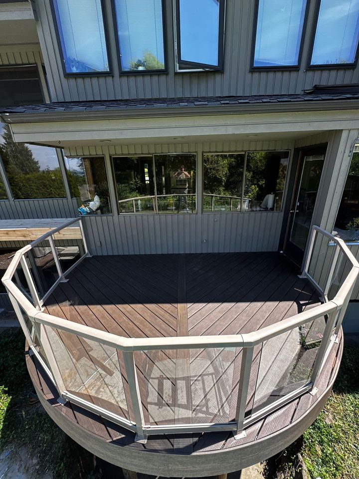 A wooden deck with stairs leading up to it is in front of a house.