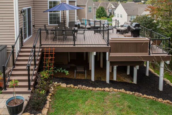 A wooden deck with stairs leading up to it is in front of a house.