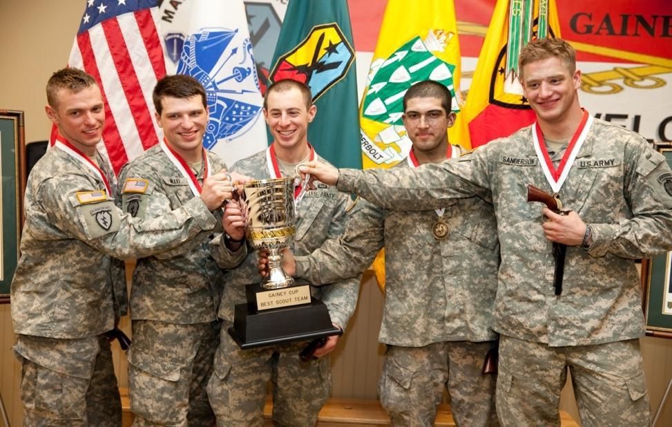 A group of soldiers holding a trophy in front of flags