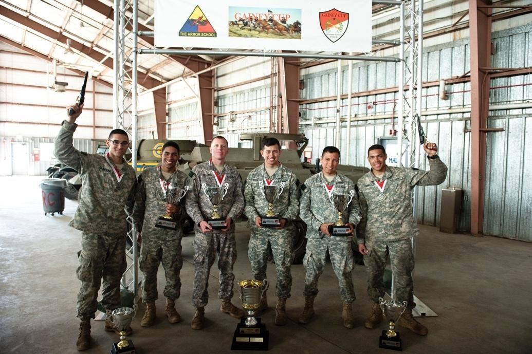 A group of soldiers are holding trophies in a warehouse.