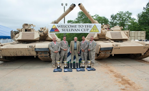 A group of soldiers standing in front of a sign that says welcome to the sullivan cup.
