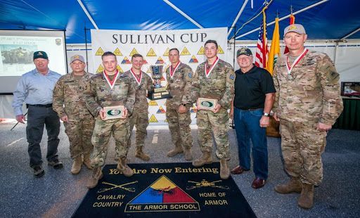 A group of soldiers are posing for a picture in front of a banner that says sullivan cup.