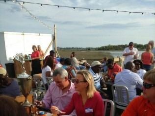 People seated at outdoor tables, eating and socializing.