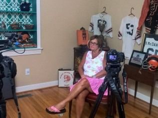 Woman in pink dress and flip-flops sits for an interview.