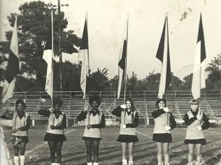 Six flag corps members on a football field
