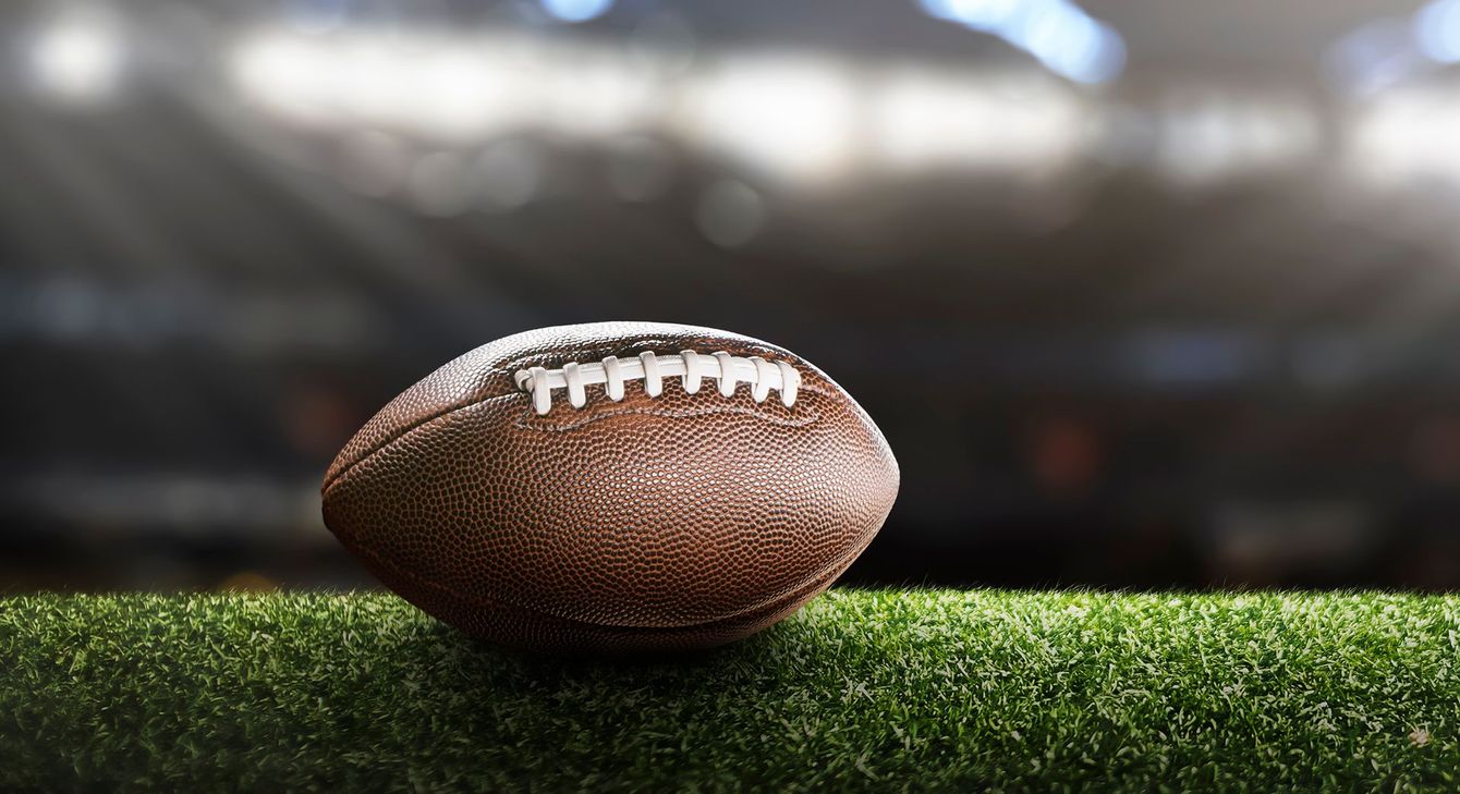 Football on a green field at a stadium.