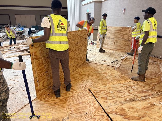 Workers in yellow vests installing plywood flooring.