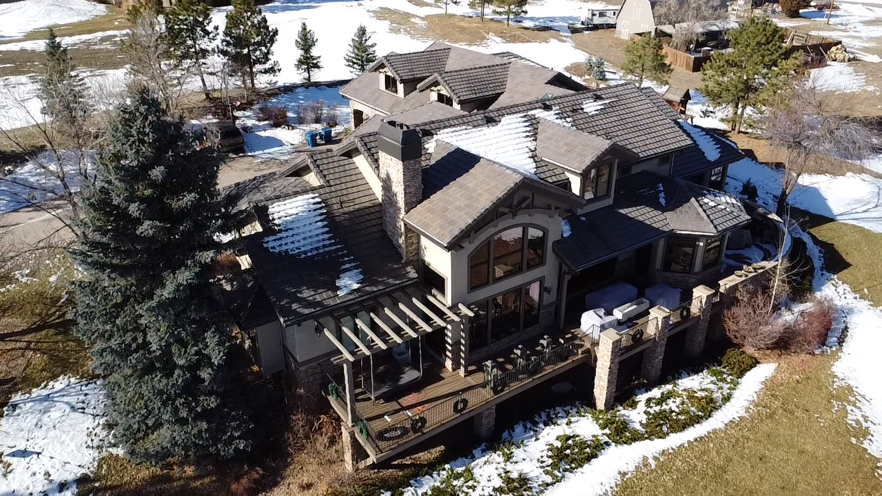 A large house is being built in the middle of a dirt field. Roofers in image