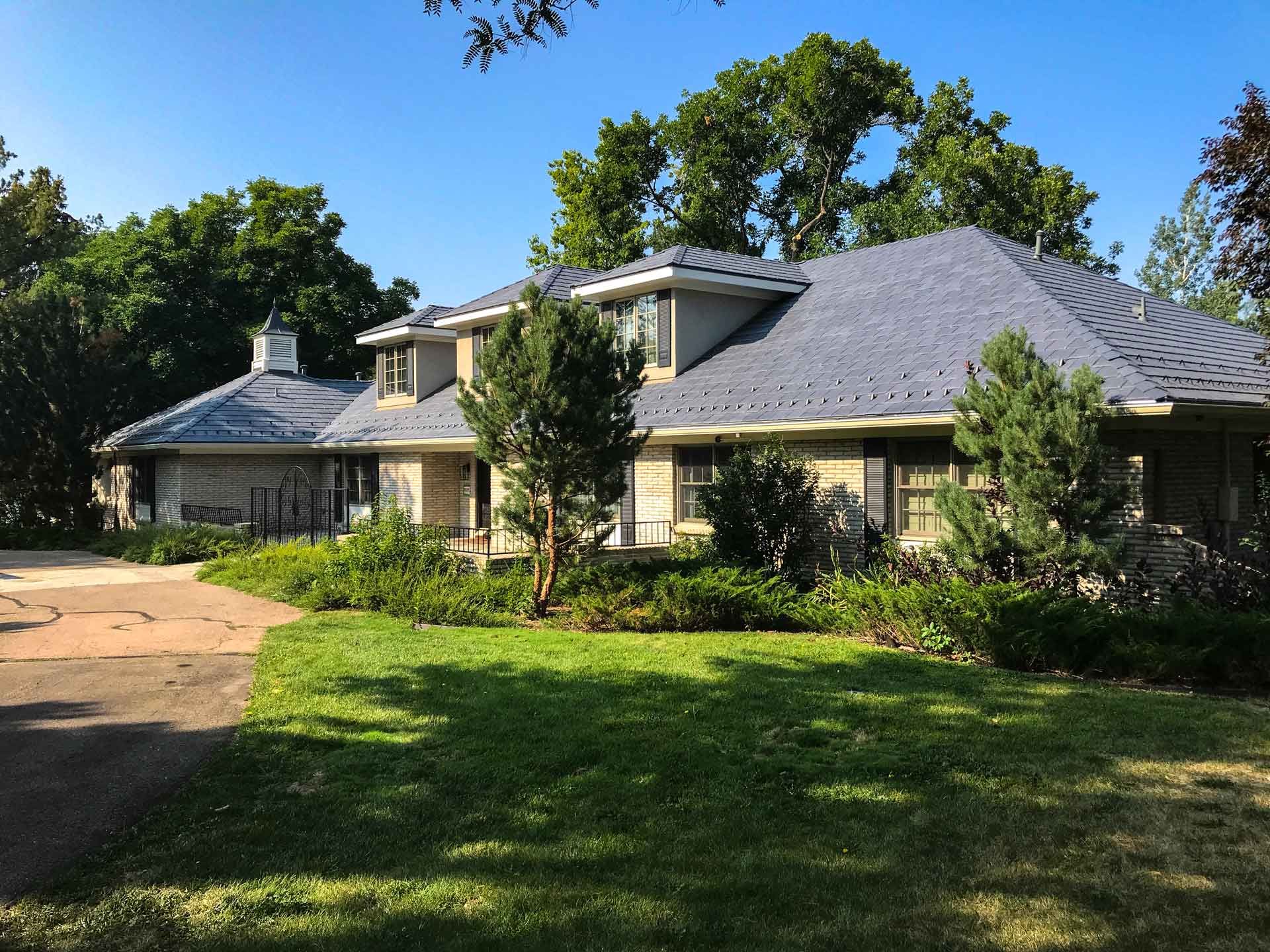 A large house with a gray roof and a driveway