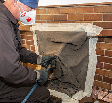 A man wearing a mask is working on a fireplace
