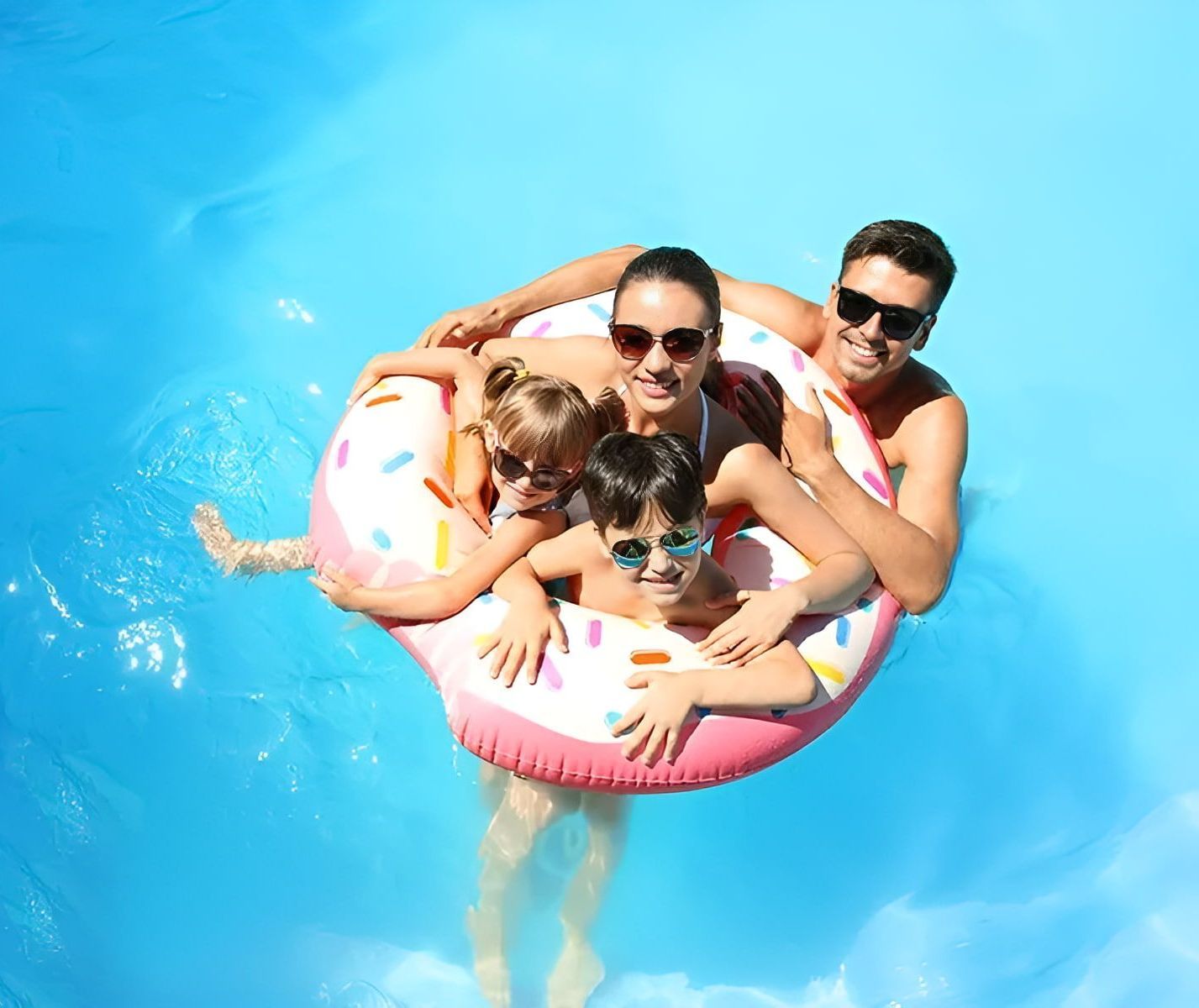 A Family Is Floating On An Inflatable Donut In A Swimming Pool — Holiday Coast Pools & Water In Coffs Harbour, NSW