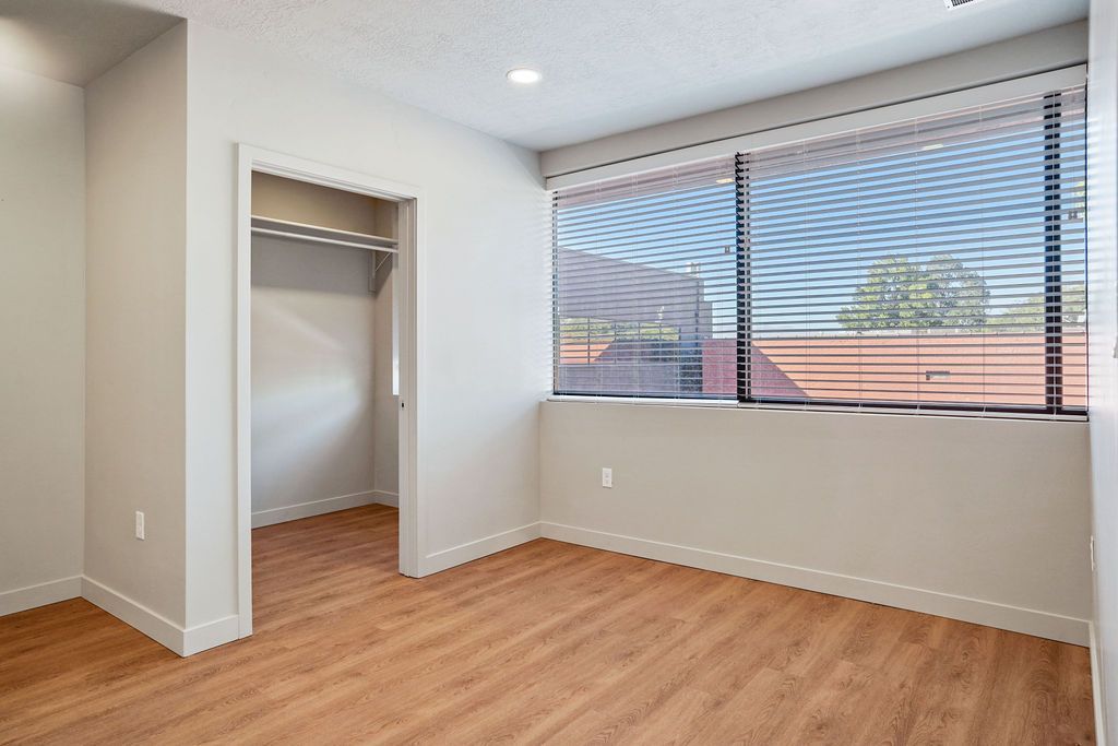 An empty bedroom with hardwood floors and a large window.