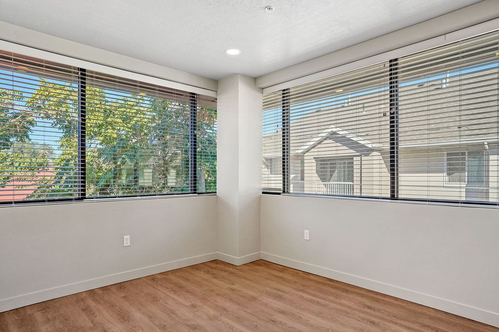 An empty room with hardwood floors and lots of windows.