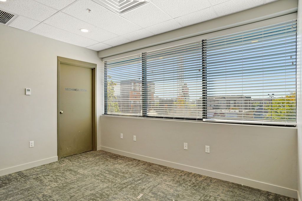 An empty room with a large window and blinds.