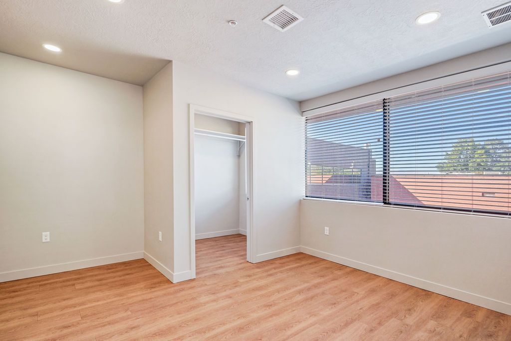 An empty room with hardwood floors and a large window.