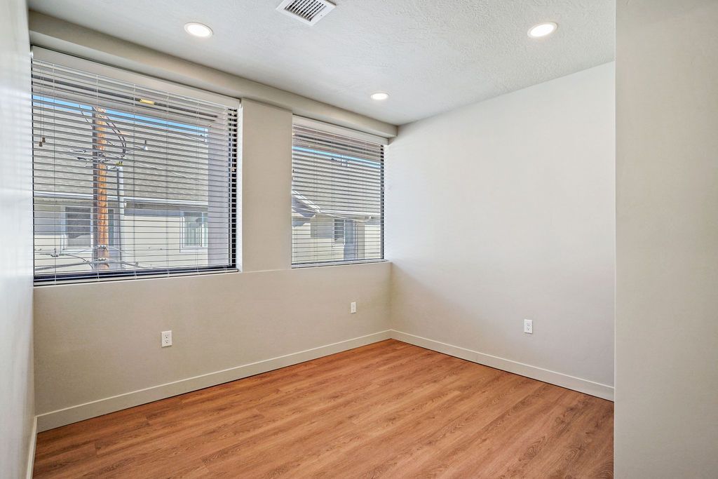 An empty room with hardwood floors and two windows.