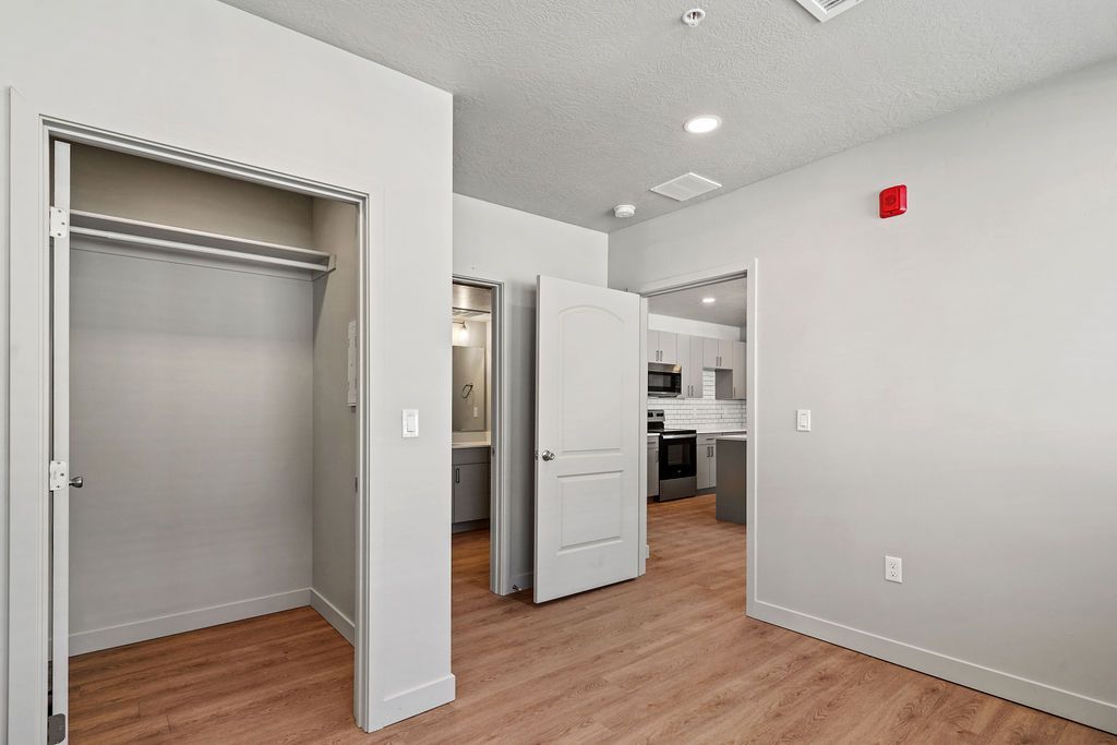 A bedroom with hardwood floors , a closet , and a kitchen.