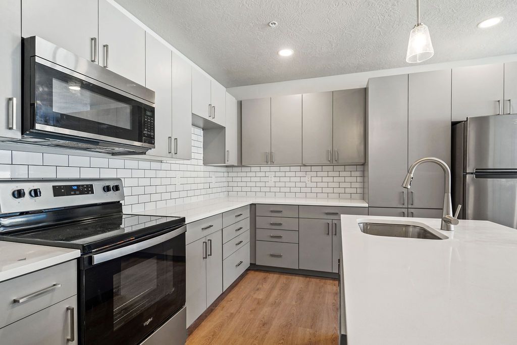 A kitchen with stainless steel appliances and white cabinets.