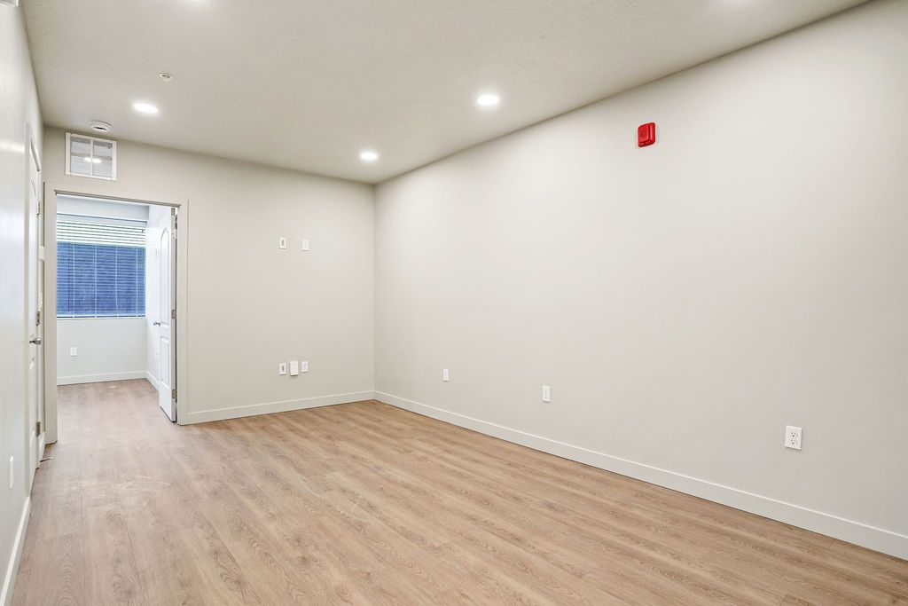 A large empty room with hardwood floors and white walls.