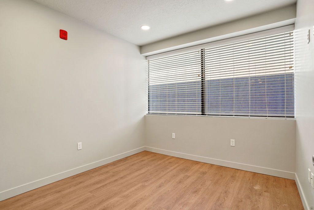 An empty room with hardwood floors and a large window.