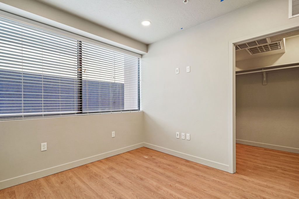 An empty room with hardwood floors and a large window.