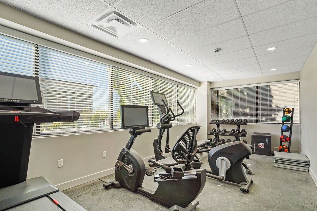 A gym with exercise bikes , treadmills , and a large window.
