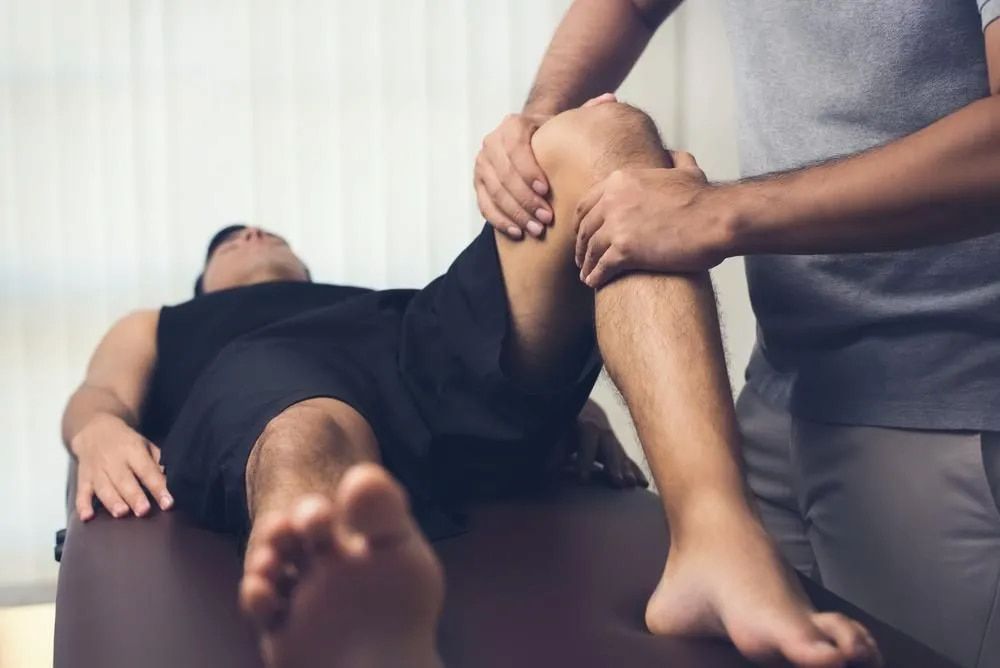 Physiotherapist Examining a Man's Knee — Living Well Chiropractic Coffs Harbour in Coffs Harbour, NSW