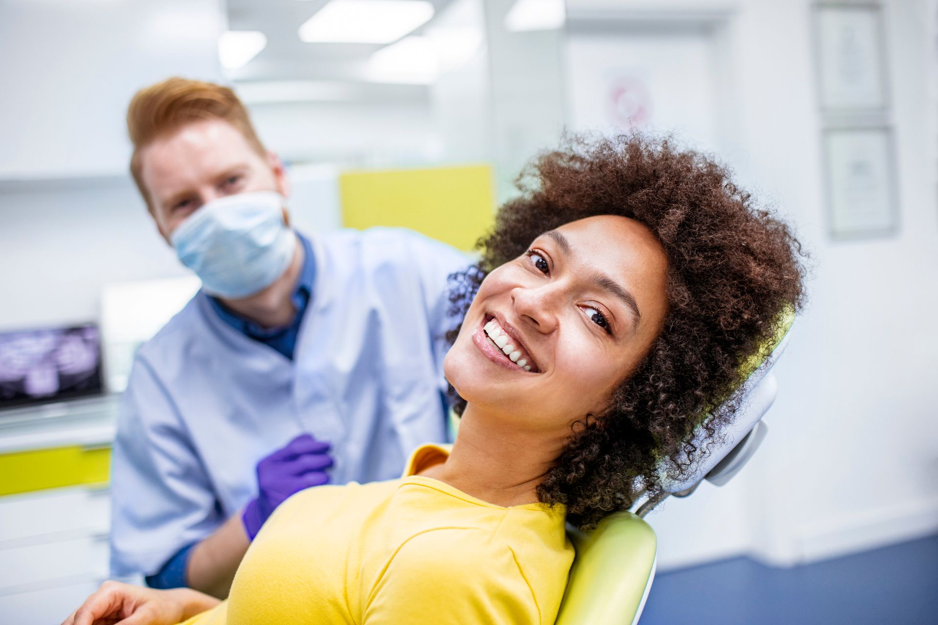 A woman is smiling while sitting in a dental chair.