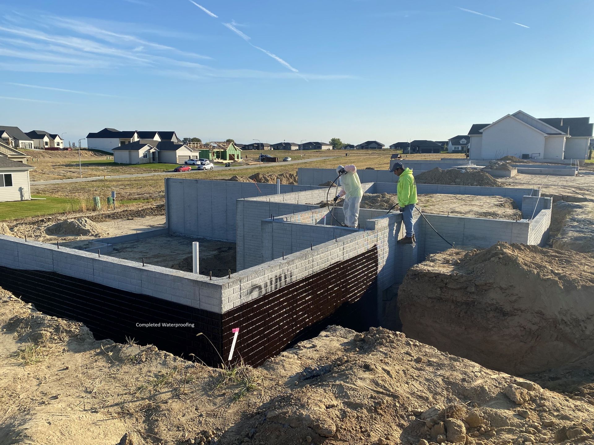 Men waterproofing the foundation of new home