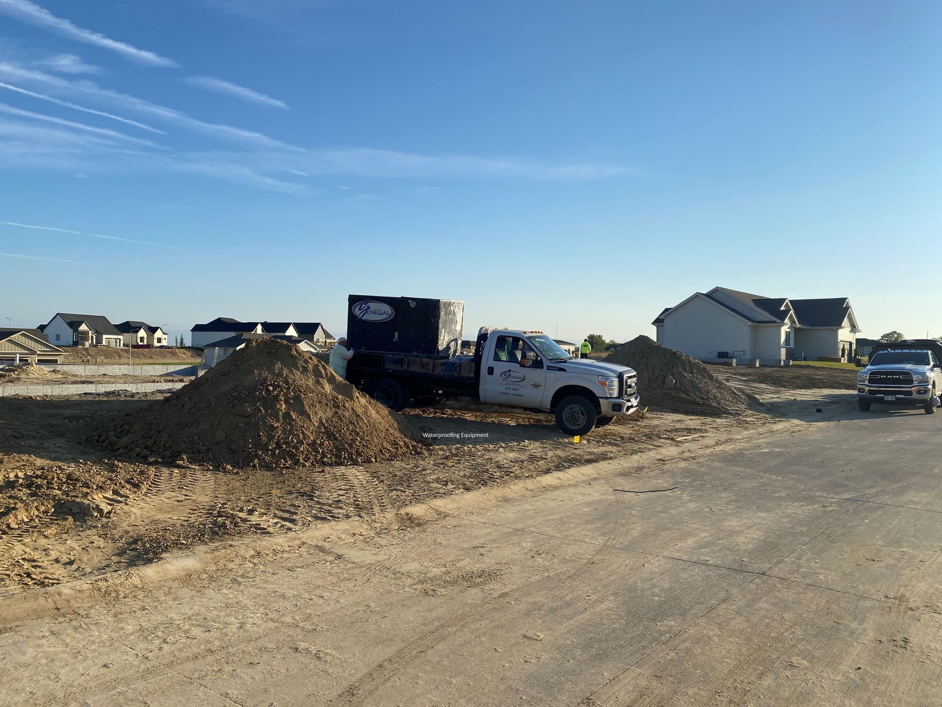 a white truck is driving down a dirt road next to a pile of dirt .