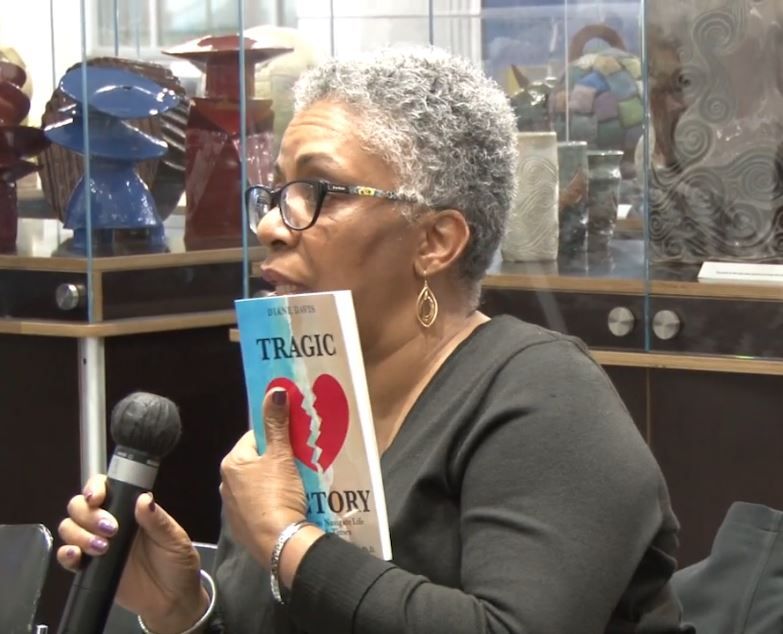 A woman is holding a book titled tragic  victory Diane Davis author