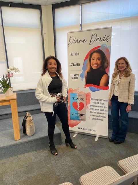 Two women standing in front of a diana davis banner