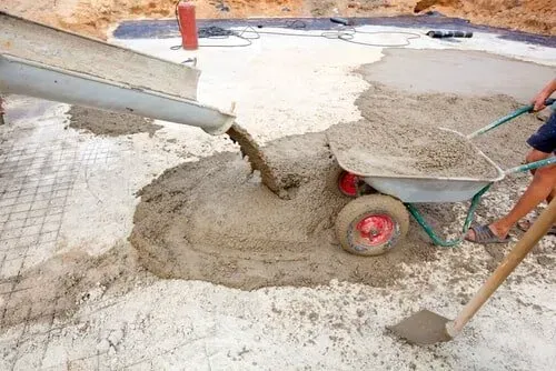 A Person Is Pouring Concrete Into A Wheelbarrow — Doug's Concrete Pumping Pty Ltd in Glenella, QLD