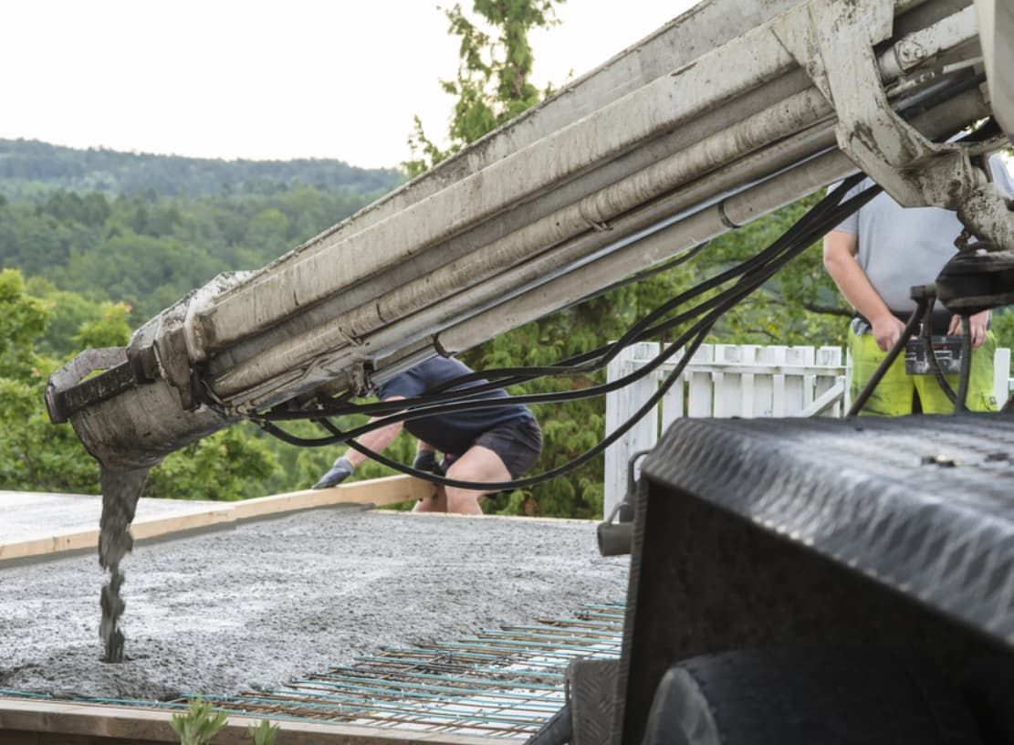 A Man Is Pouring Concrete From A Crane Onto A Concrete Surface — Doug's Concrete Pumping Pty Ltd in Glenella, QLD