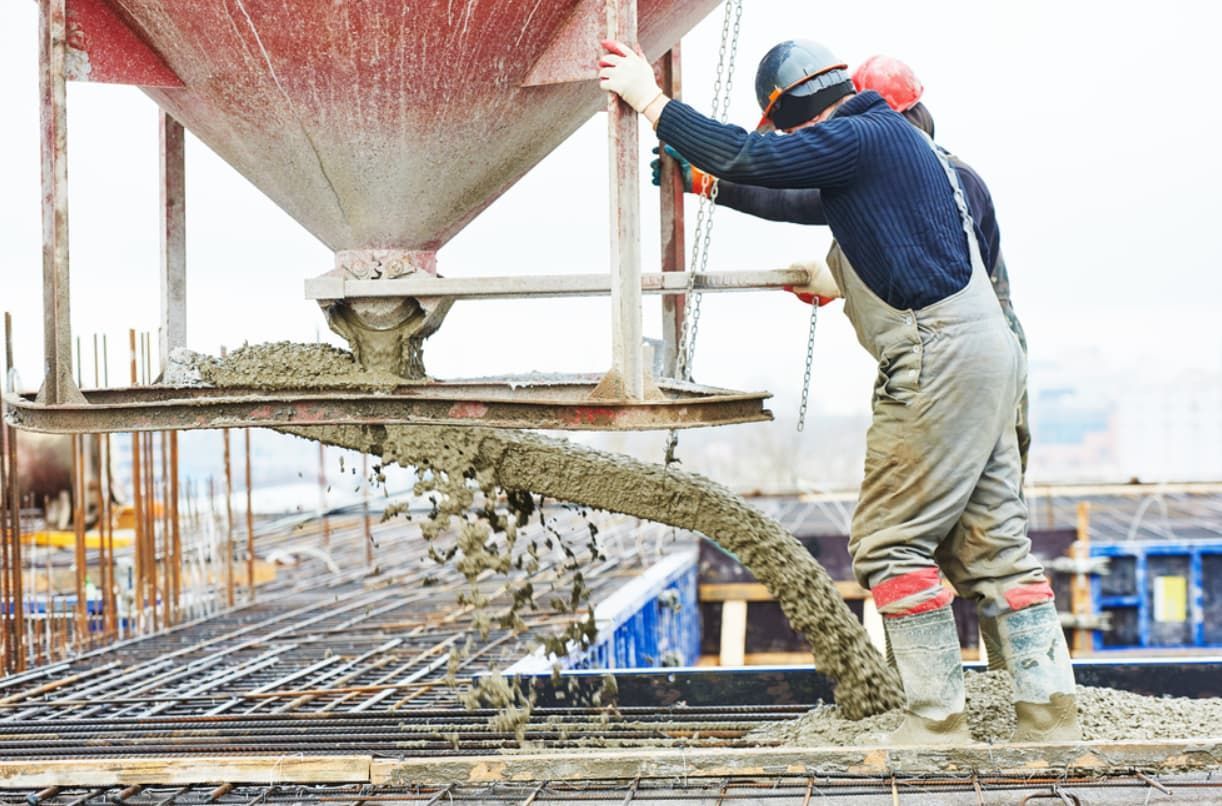 A Man Is Pouring Concrete Into A Concrete Mixer At A Construction Site — Doug's Concrete Pumping Pty Ltd in Glenella, QLD