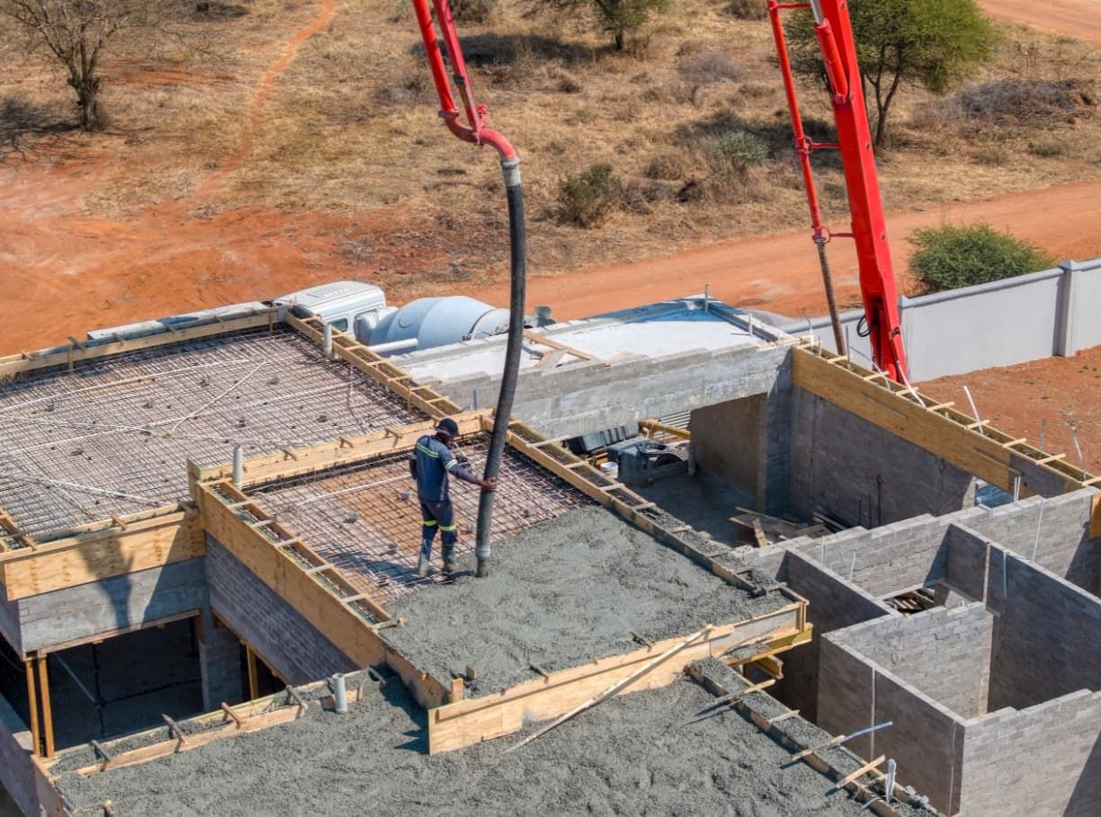 A Man Is Pouring Concrete On Top Of A Building Under Construction — Doug's Concrete Pumping Pty Ltd in Glenella, QLD