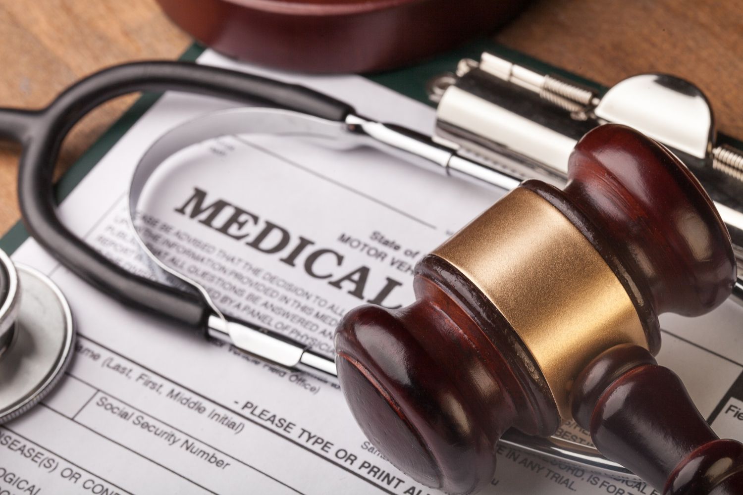Gavel, stethoscope, and medical form on a clipboard, representing legal and medical aspects.