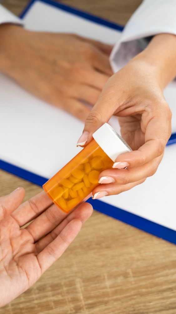 Doctor handing a prescription bottle of pills to a patient.