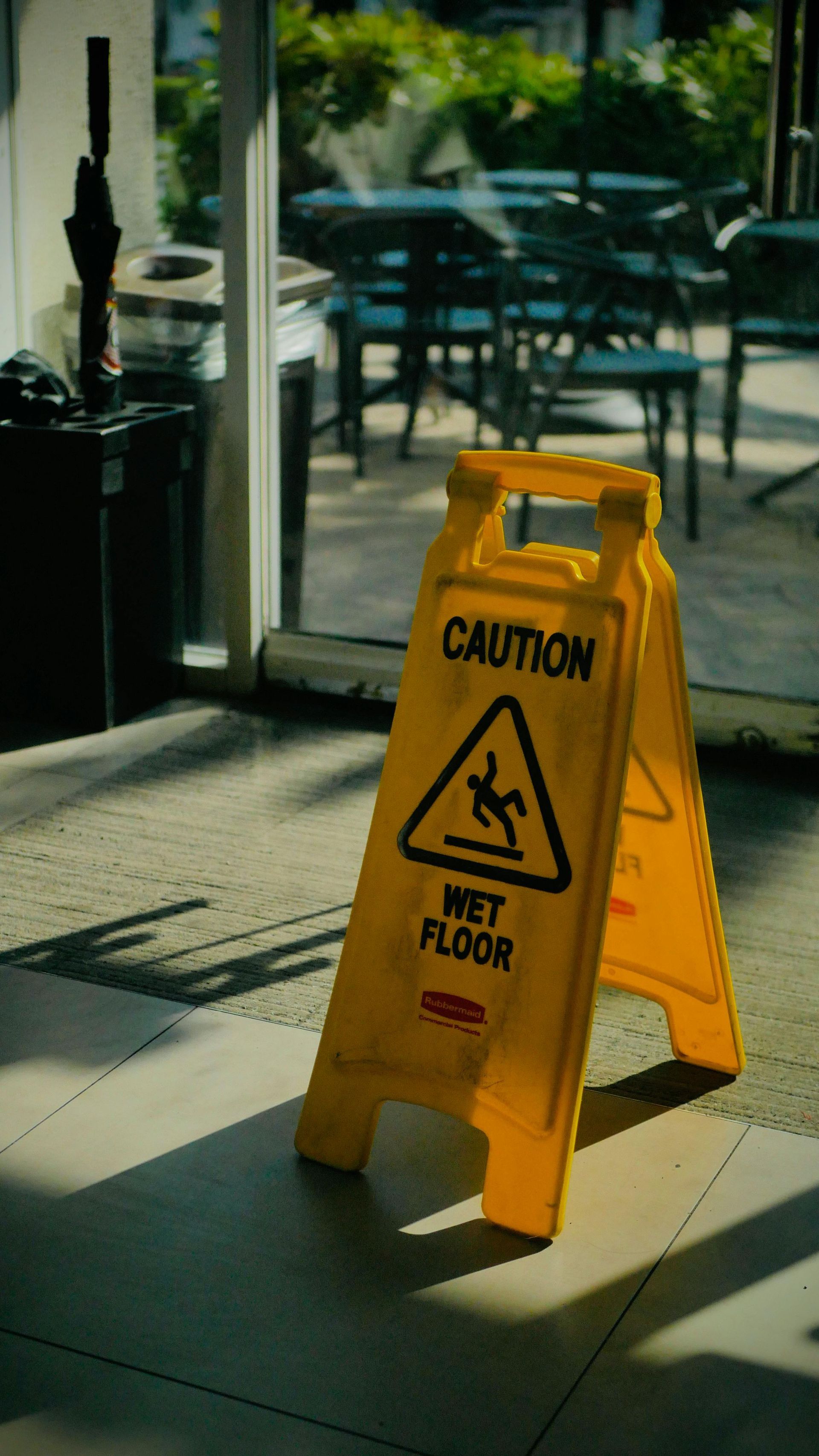 Yellow caution sign on a wet floor inside a restaurant near a window.
