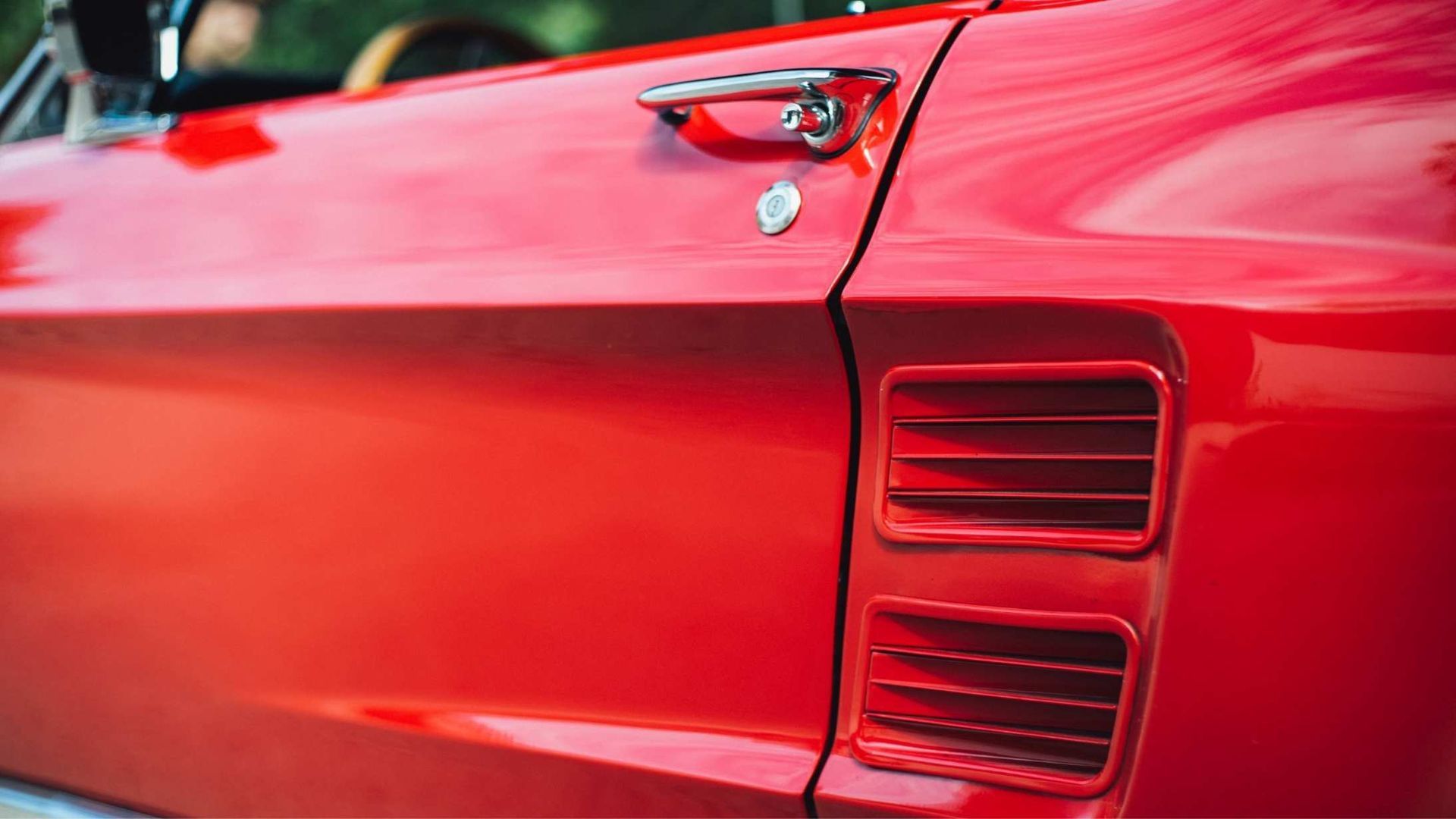 Red classic car door, with chrome handle and side vent.