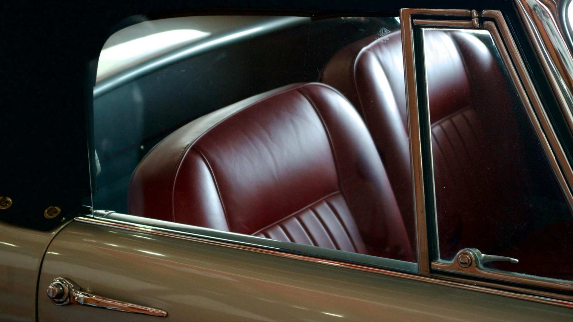 Red leather car seats inside a classic convertible with the top down, a silver exterior, and a black fabric top.