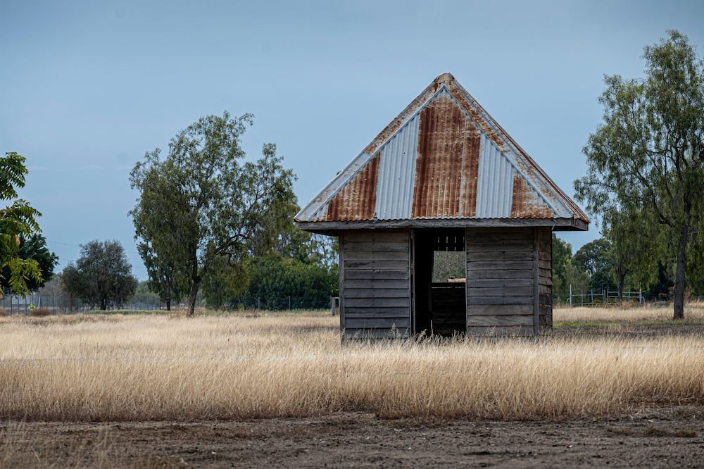 An Old Wooden Building With A Rusty Tin Roof In The Middle Of A Field — Splash-A-Bout Swim School Pty Ltd In Biloela, QLD