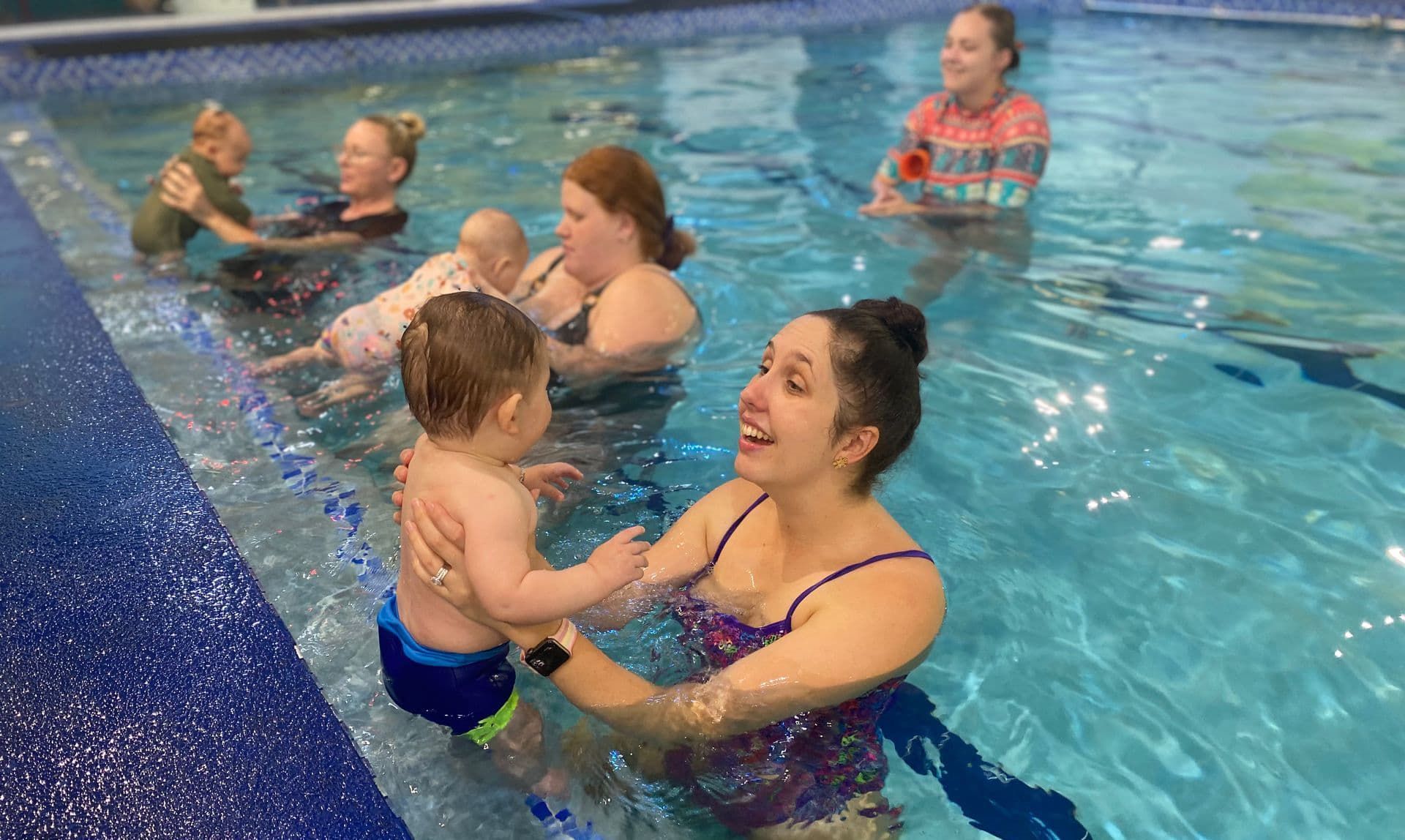 Young Swimming Trainer Talking To Babies In Swimming Pool — Splash-A-Bout Swim School Pty Ltd In Park Avenue, QLD
