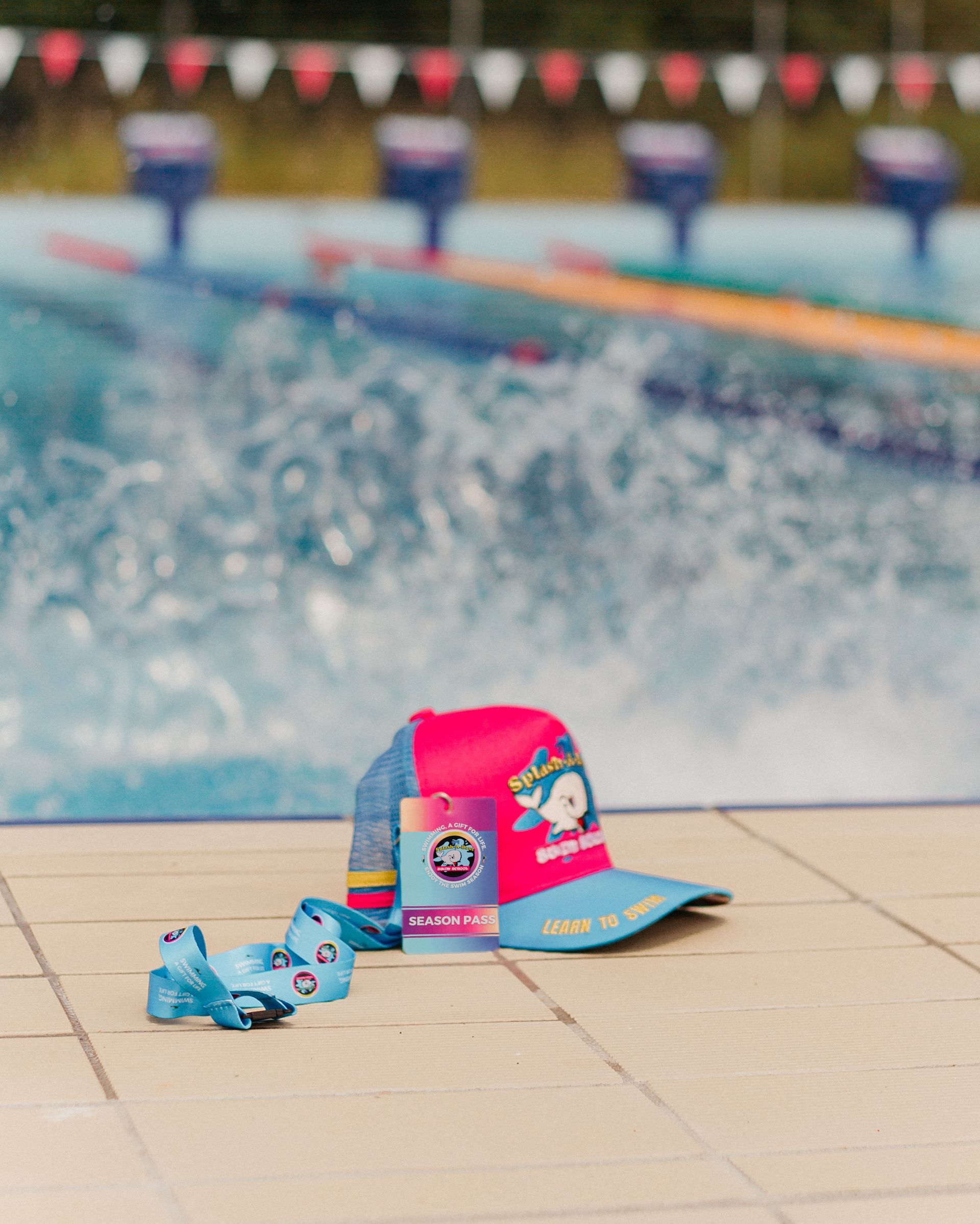 A Hat And A Medal Are On The Ground In Front Of A Swimming Pool — Splash-A-Bout Swim School Pty Ltd In Park Avenue, QLD
