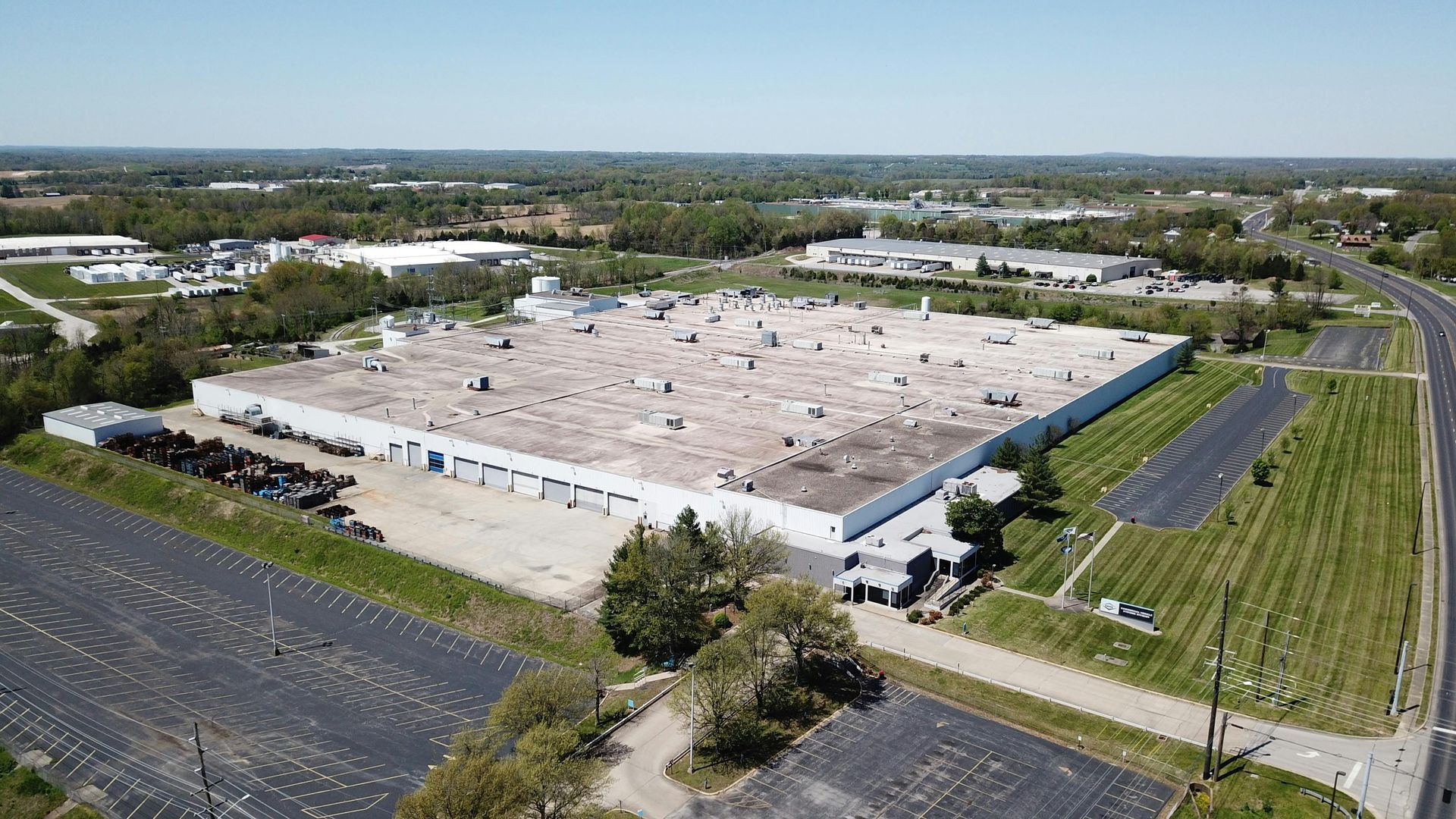 An aerial view of a large white commercial building and roof