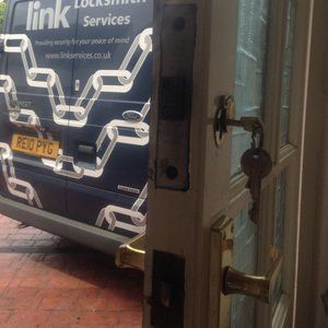 Lock repair in a wooden front door with our company van parked in the background.