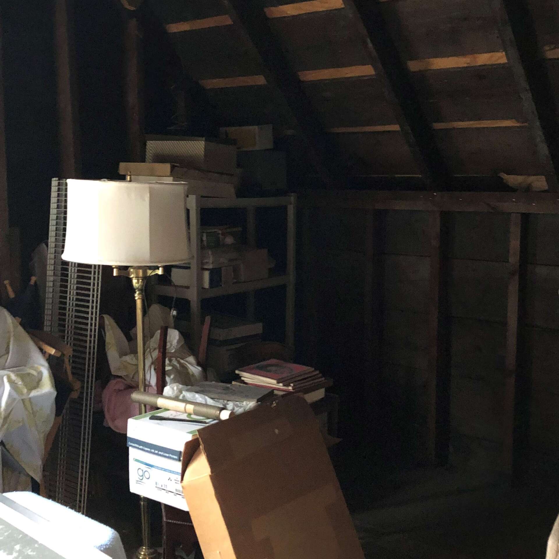 An attic with a lamp and boxes on the floor