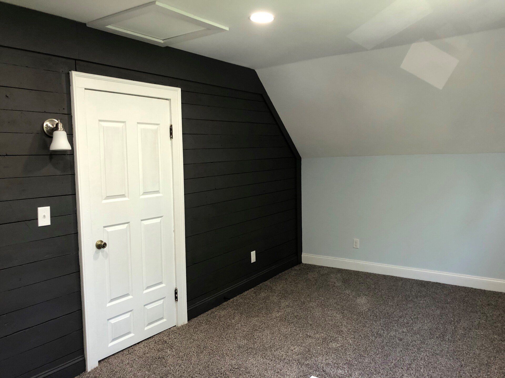 An empty room with black walls and a white door.