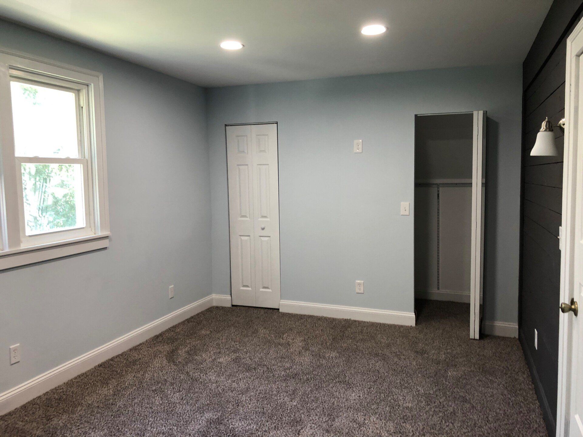 An empty bedroom with a closet and a window.