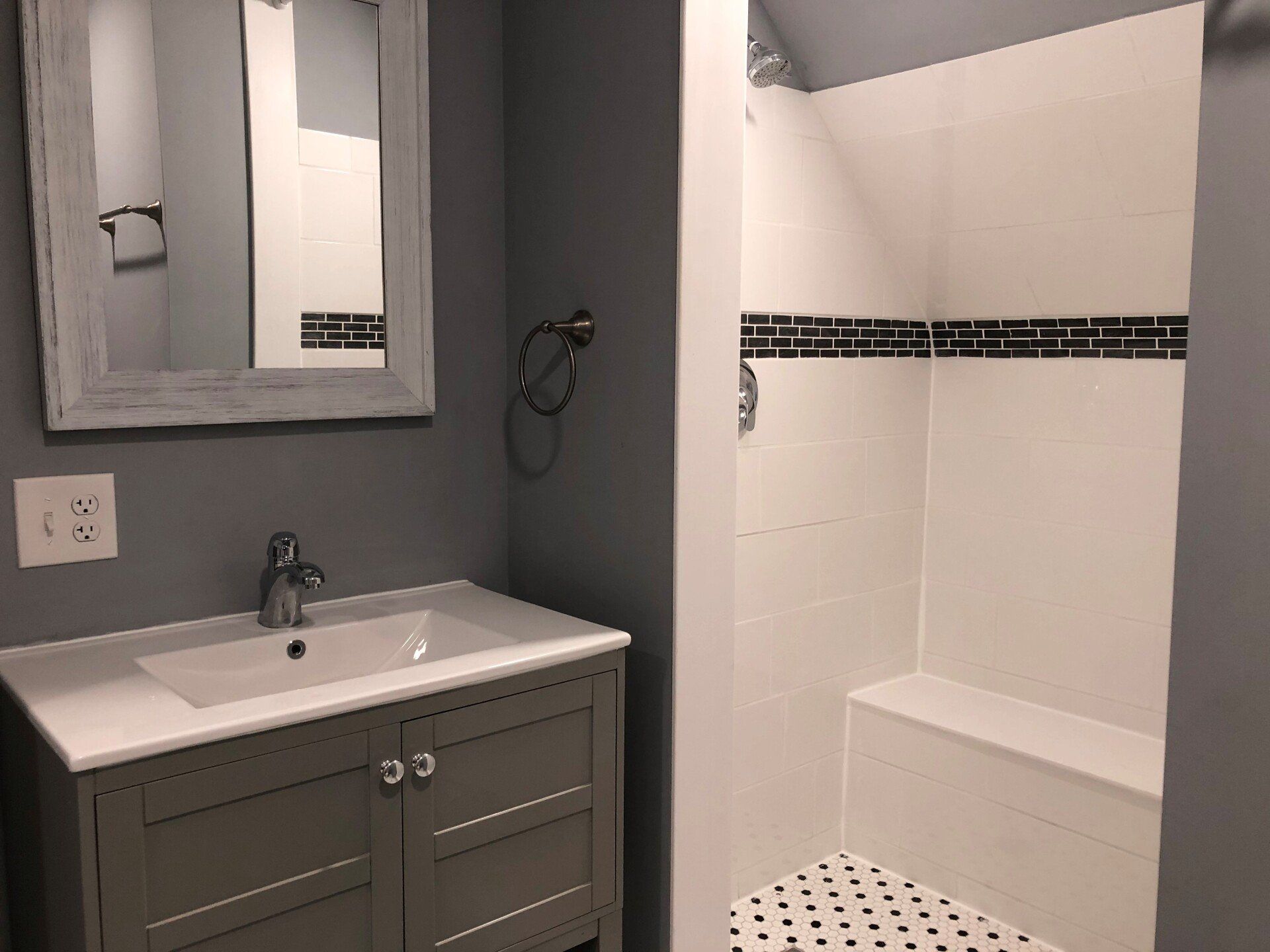 A bathroom with a sink , mirror and shower.